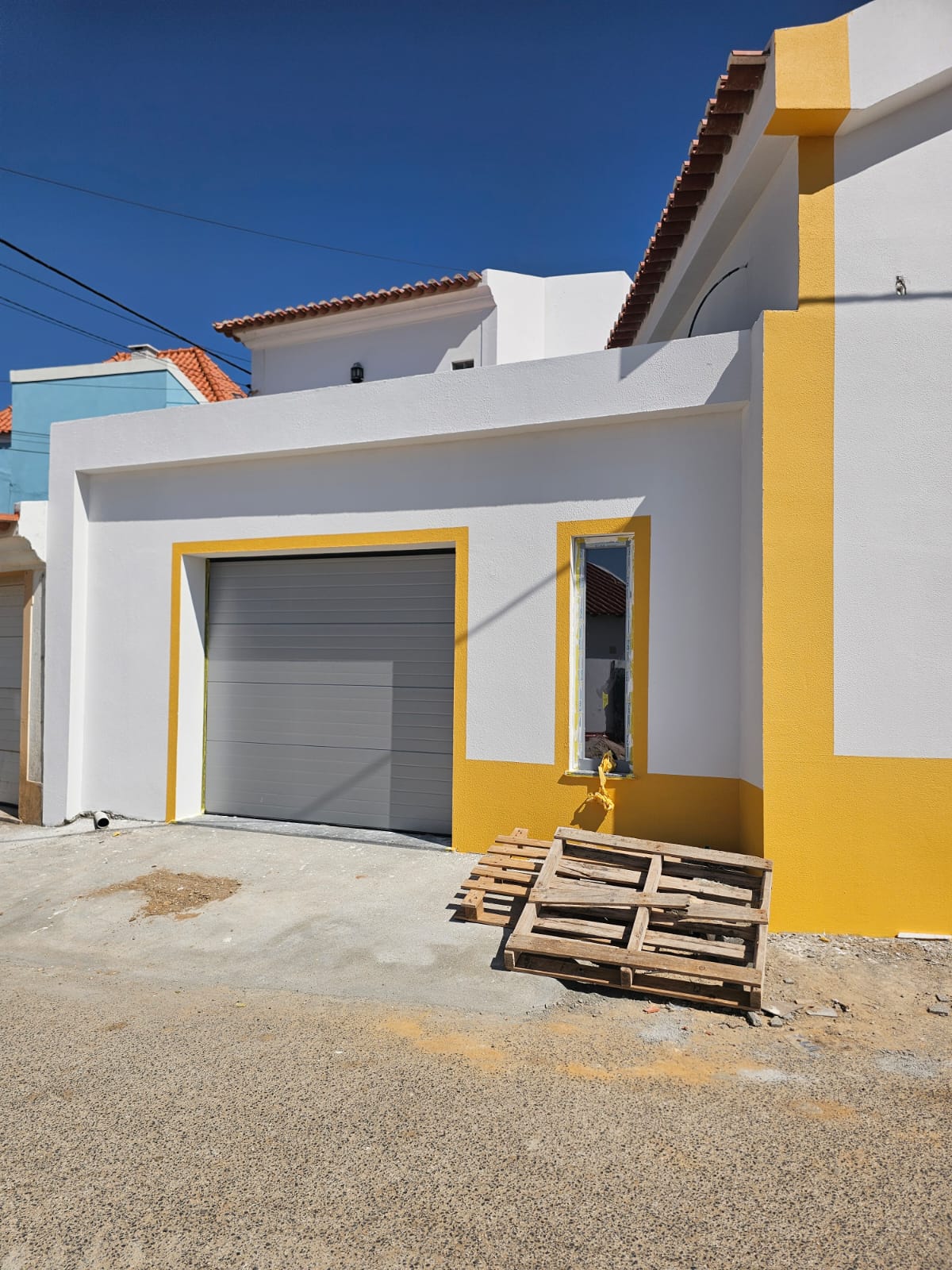 Portão de garagem cinza integrado na fachada de uma moradia