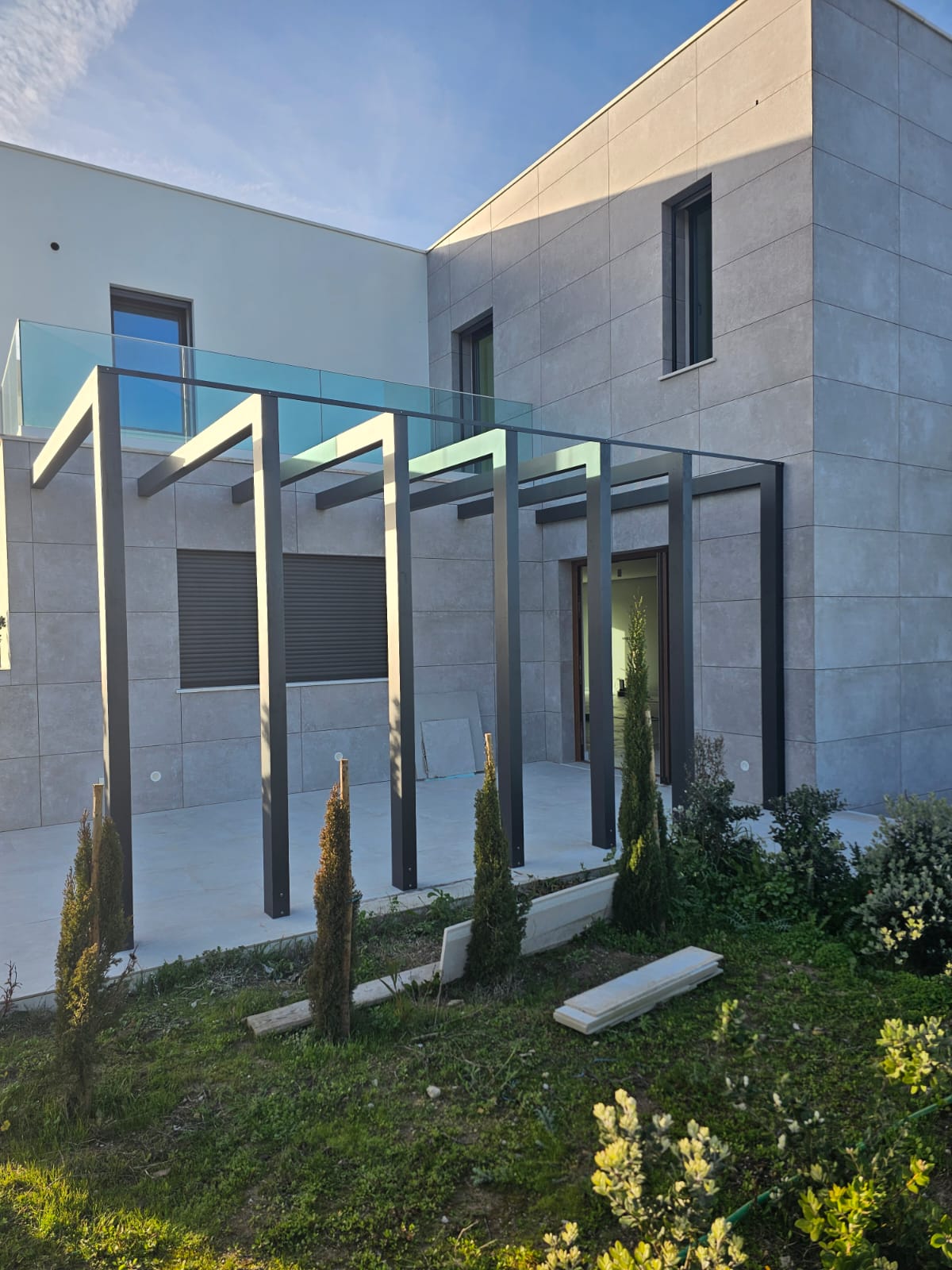 Pérgola metálica antracite com cobertura de vidro numa moradia